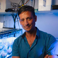 Headshot of Martin in the lab with equipment behind him.