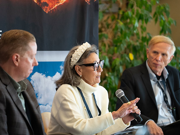 AWE 2025 3 A speaker on a panel talks in the microphone as two others on the panel look on.