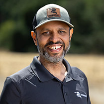 Headshot of Anukool wearing a hat and smiling outside.