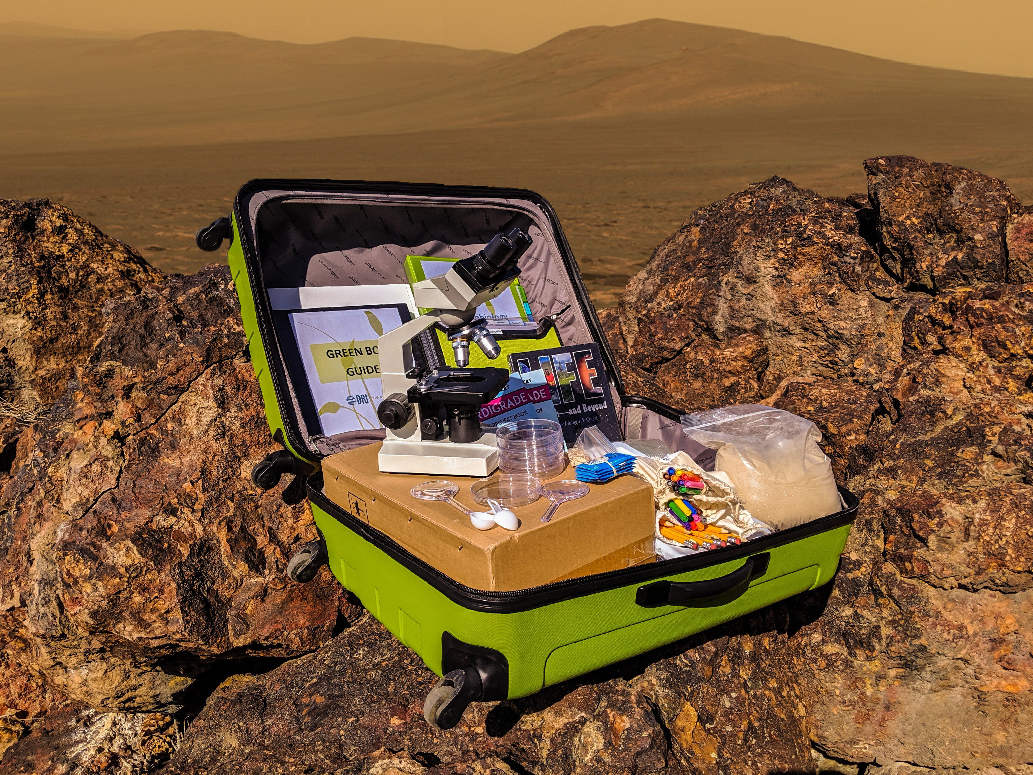 A green suitcase filled with science experiment materials sits open on a rock with the landscape of Mars in the background. 