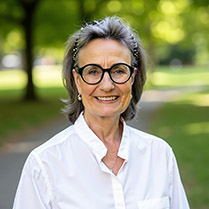 Headshot of Marybel Batjer outside in front of a green park with trees wearing glasses and white shirt. 