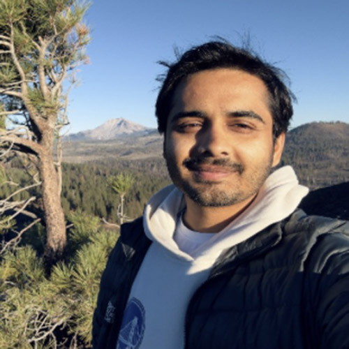 Bishal Lamichhane Group Page Selfie style photo of Bishal with a tree and mountain in the background.