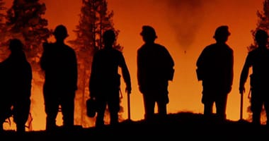 firefighters looking at a wildfire blazing