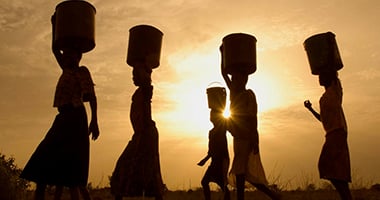 a group of women carrying baskets of water on top of their heads