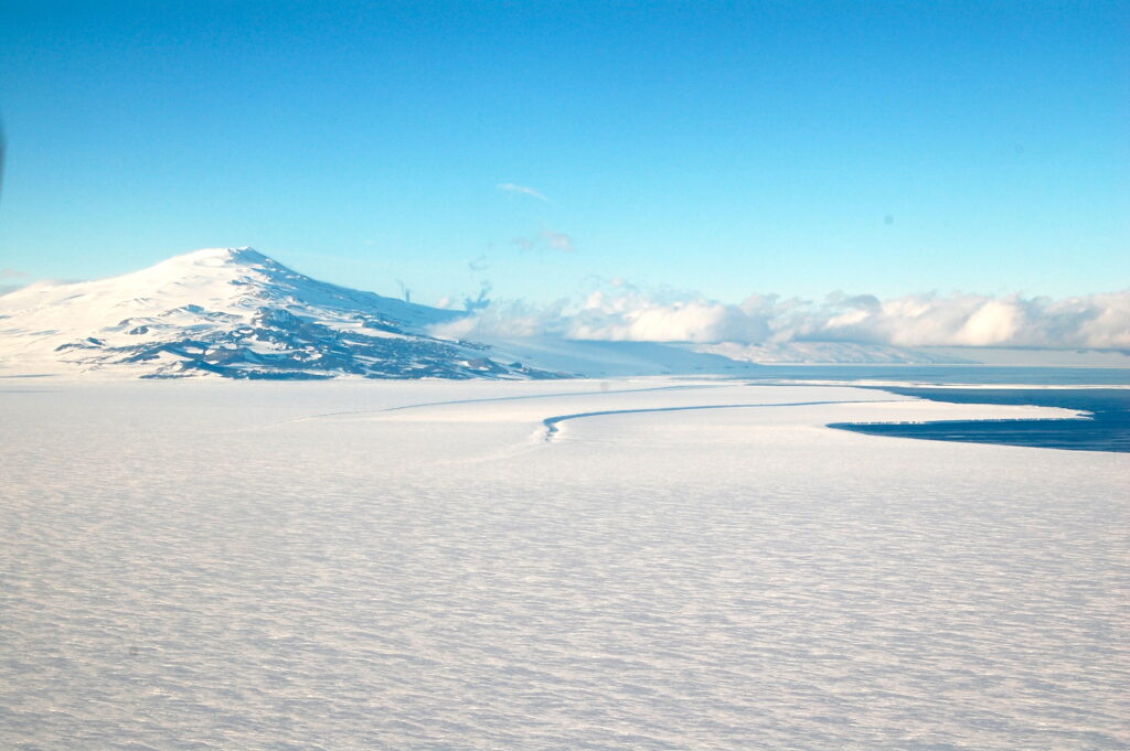 An image of an Antarctic ice sheet with a hill on one side and a lake on the other