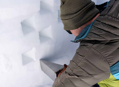 Researcher taking a snow sample from a wall of snow.