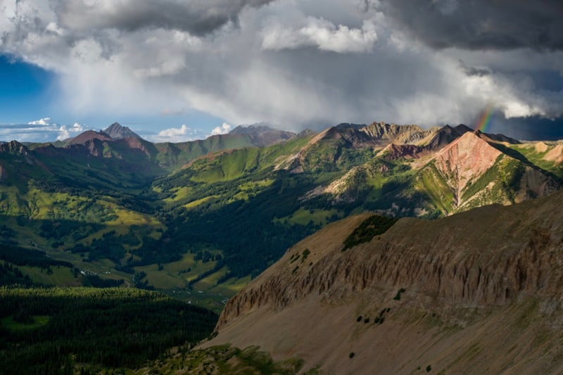 A summer monsoon rain event brings dark clouds and a rainbow to the East River watershed of Colorado.