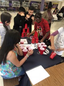 Students participate in a STEM activity by stacking cups to make pyramids.