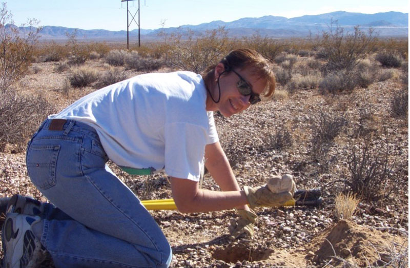 female digging holes in the desert