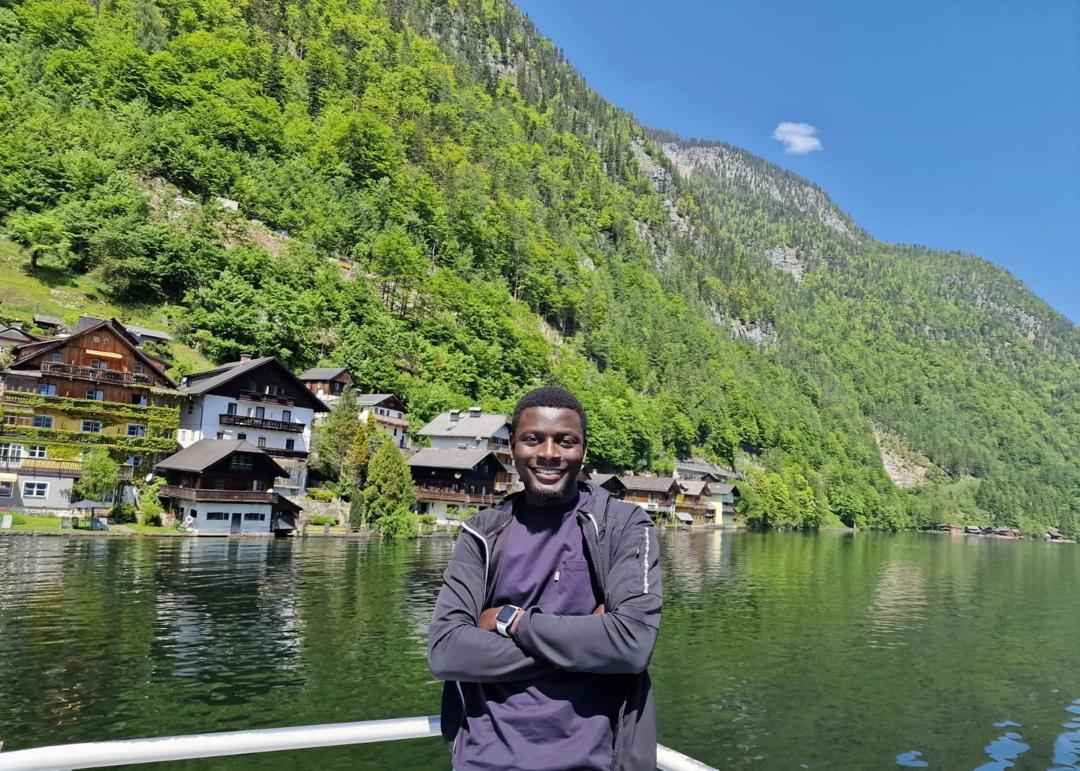 A man standing in front of a river and a vegetated mountain.