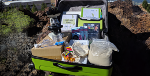 Green suitcase with supplies and binders and handouts for a STEM lesson.