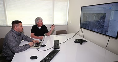 researchers look at data on a screen
