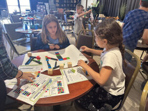 Two children at a table drawing a pathway with colored markers for the robot to follow.