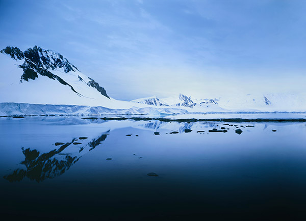 Mountain and glacier are reflected in the still water.