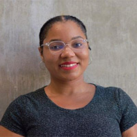 Headshot of Kendra wearing glasses against a neutral background. 