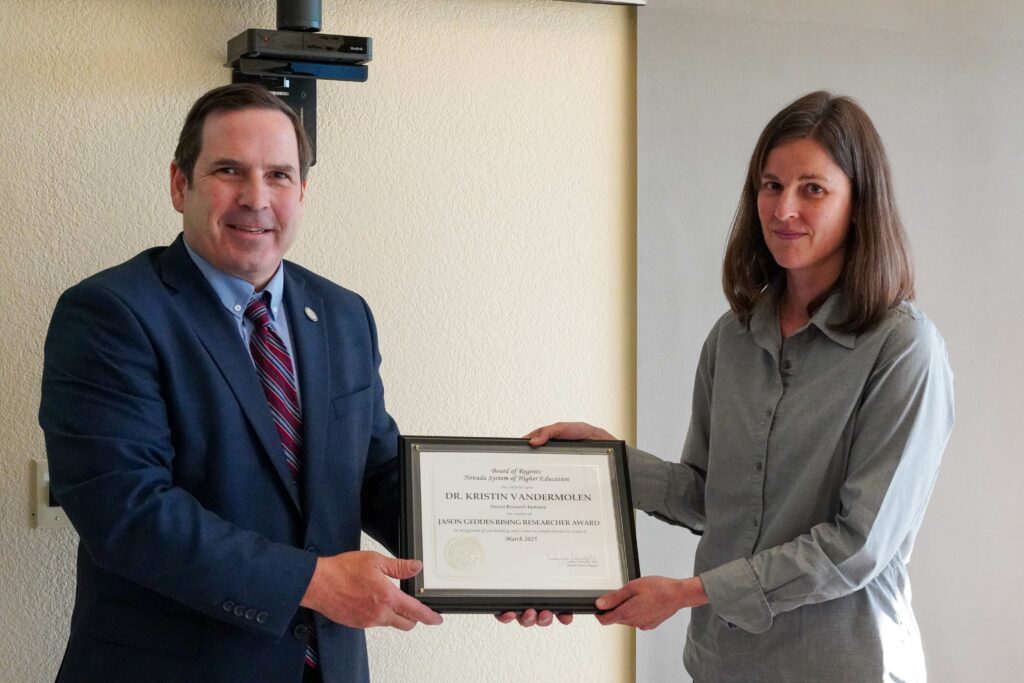 A man on the left and a woman on the right holding a plaque in the middle between them.