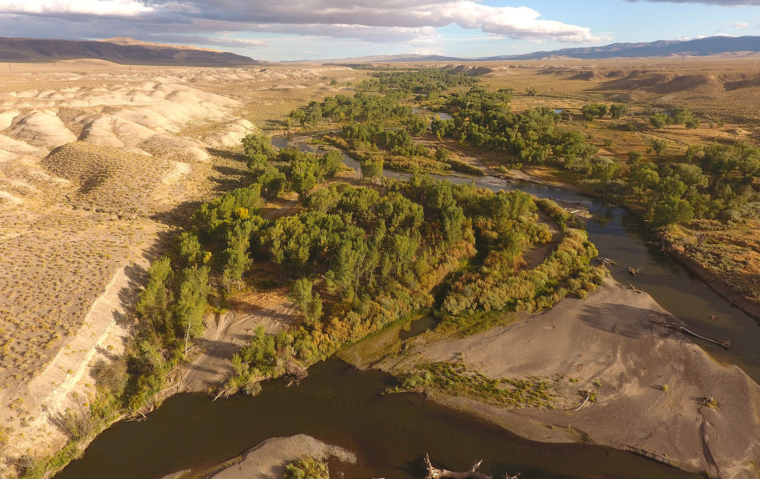 A river winding through a rocky landscape in a valley between mountains with vegetation growing at it's banks.
