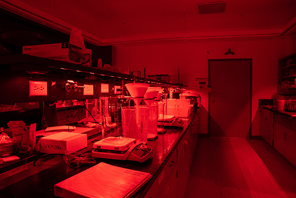 A close up of a lab center island and equipment on the counter bathed in a deep red glow. 