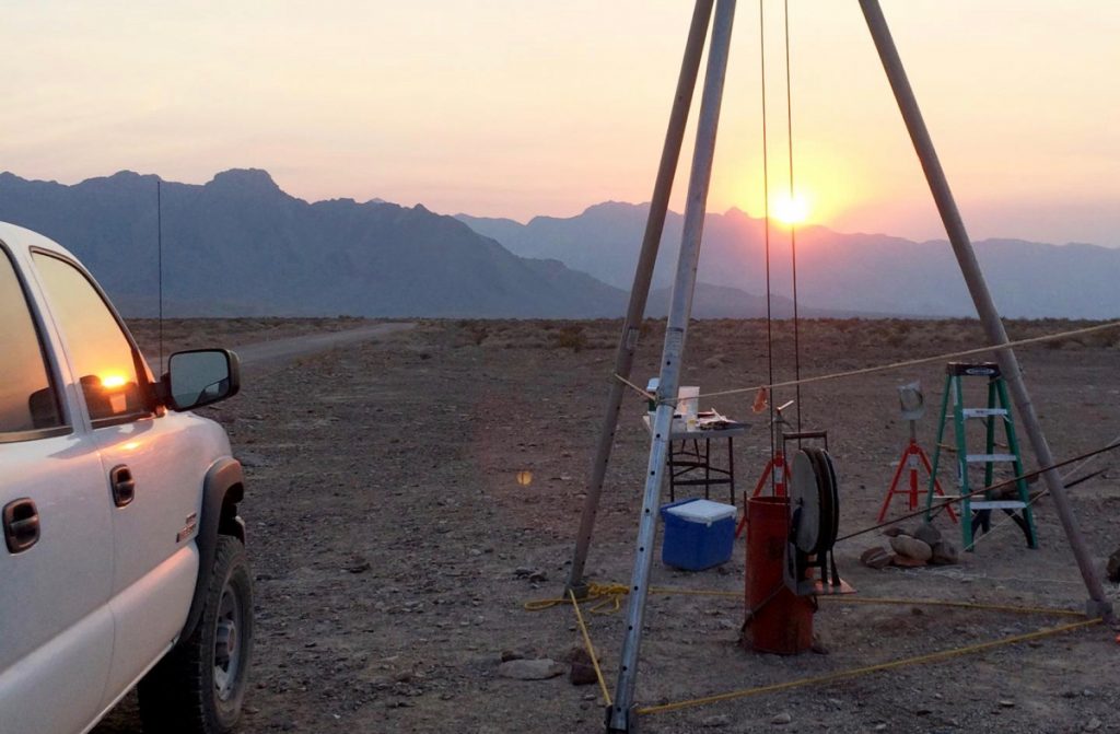 Equipment for subsurface sampling of microbes stands in Death Valley, California. Sun setting in the background.