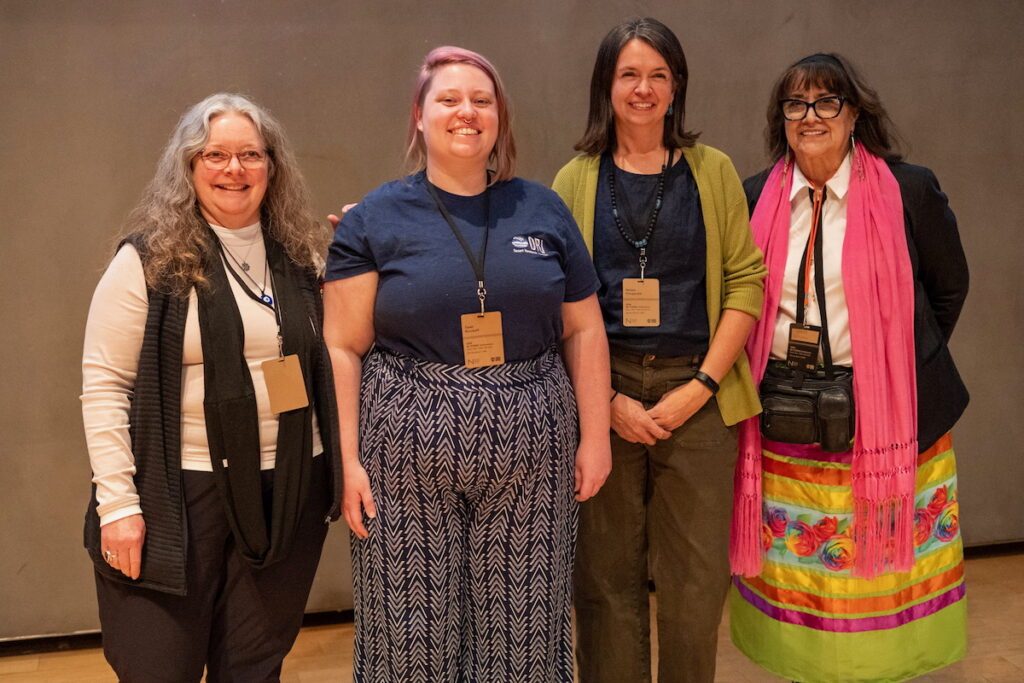 Four women standing next to each other posing for a photo.