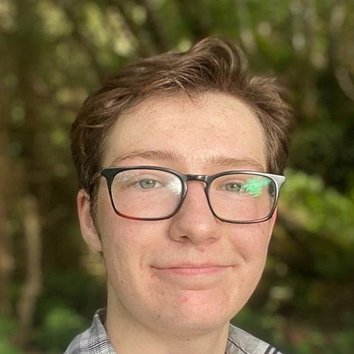 Niko Mastick Group Page Headshot of Niko taken outside and wearing glasses.