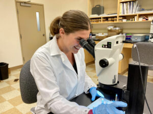 female scientist looks at slide in microscope