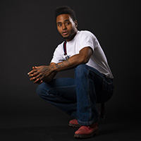 Photo of Red Crawford crouching down in front of the camera against a black background. 