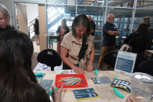 An attendee looking at the items they 3D printed with a pen on an activities table.