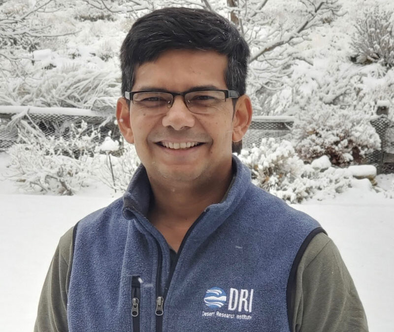 DRI Scientist smiles as he stands in front of snowy trees and backdrop