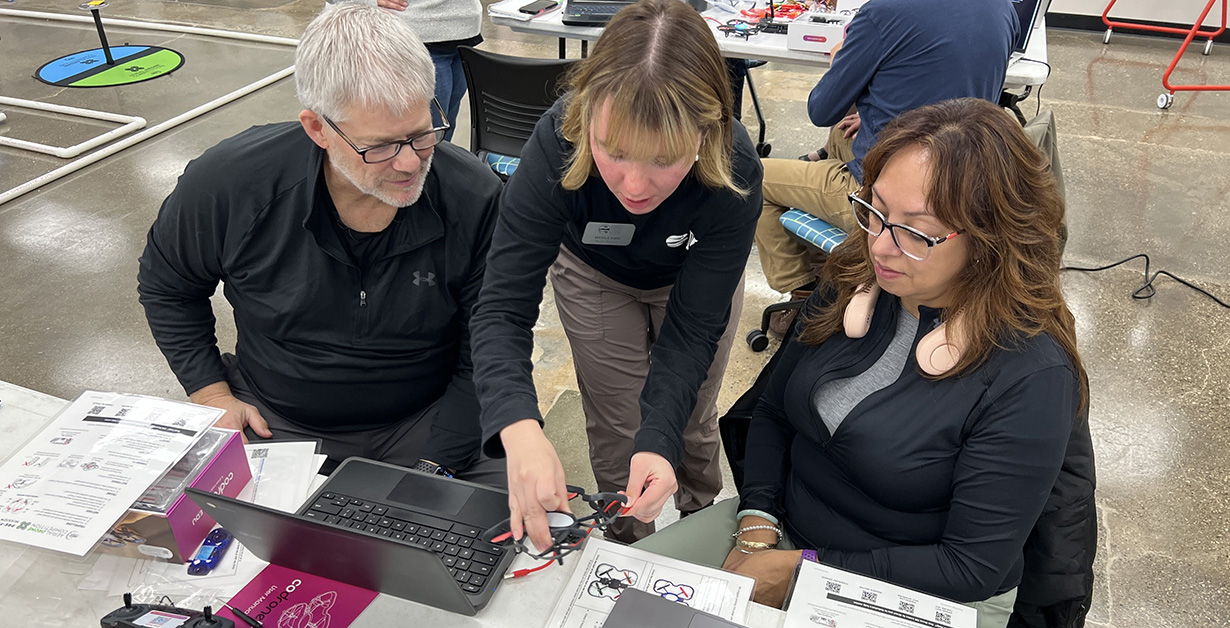 An instructor helps two educators at a training session. 