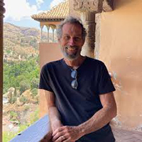 Shaun Griffin leaning on the railing of a balcony overlooking a landscape. 