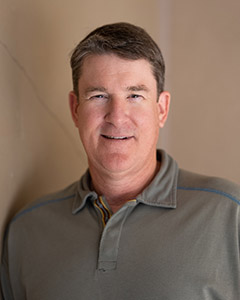 Headshot of Steve smiling and wearing a grey polo shirt against a neutral background.