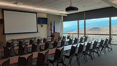 Conference room with tables and chairs facing a screen.