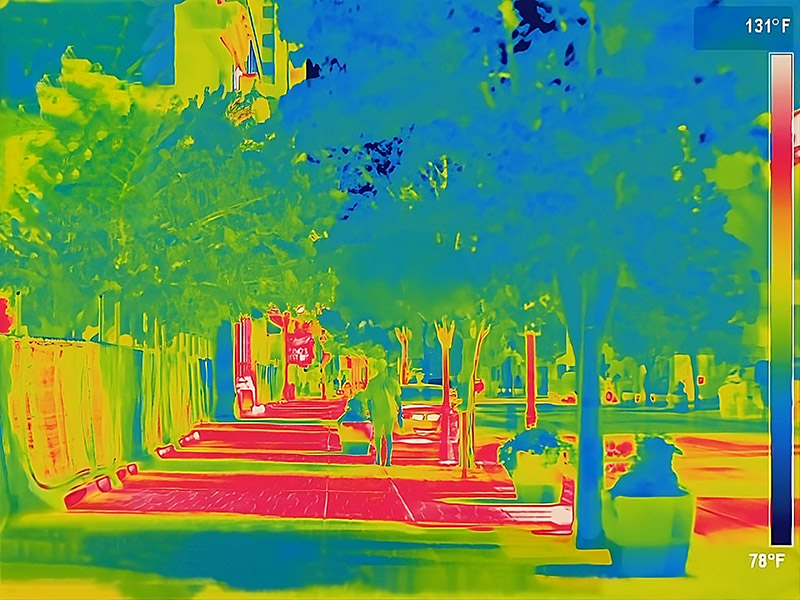 Thermal image of a sidewalk in downtown reno where the areas in red show the areas not shaded by the trees.  The shaded areas show up as greens and blues. Temperature range is indicated as 78F - 131F