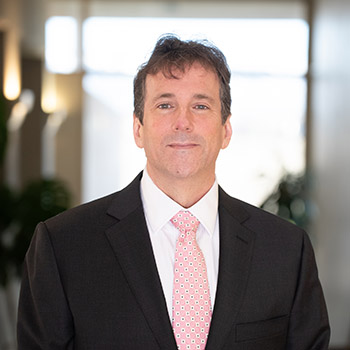 Headshot of Trey wearing a suit and tie.