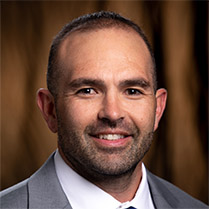 Headshot of Francisco Vega wearing a grey suit against a neutral background. 