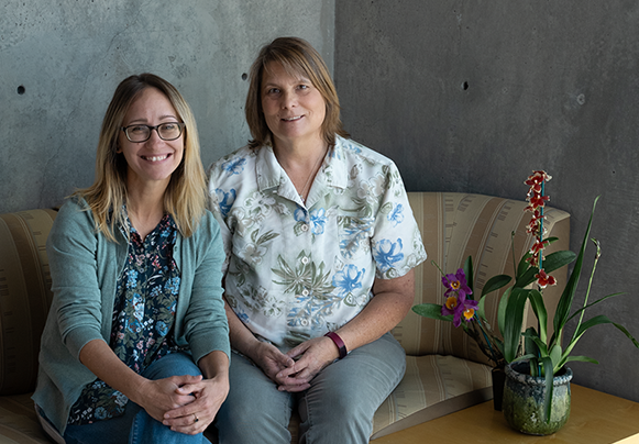 Researchers sitting together on a couch with an orchid in a planter to the side of them.