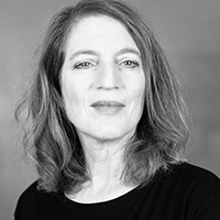 Black and White headshot of Linda wearing a black shirt against a neutral background. 