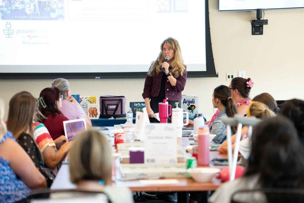 Women speaking into a microphone to a group of people.