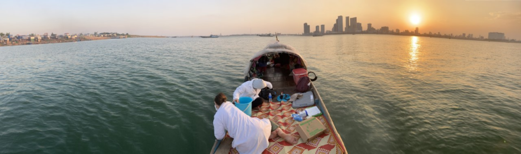 Researcher on a boat in the Mekong River, taking water samples to measure microplastics.